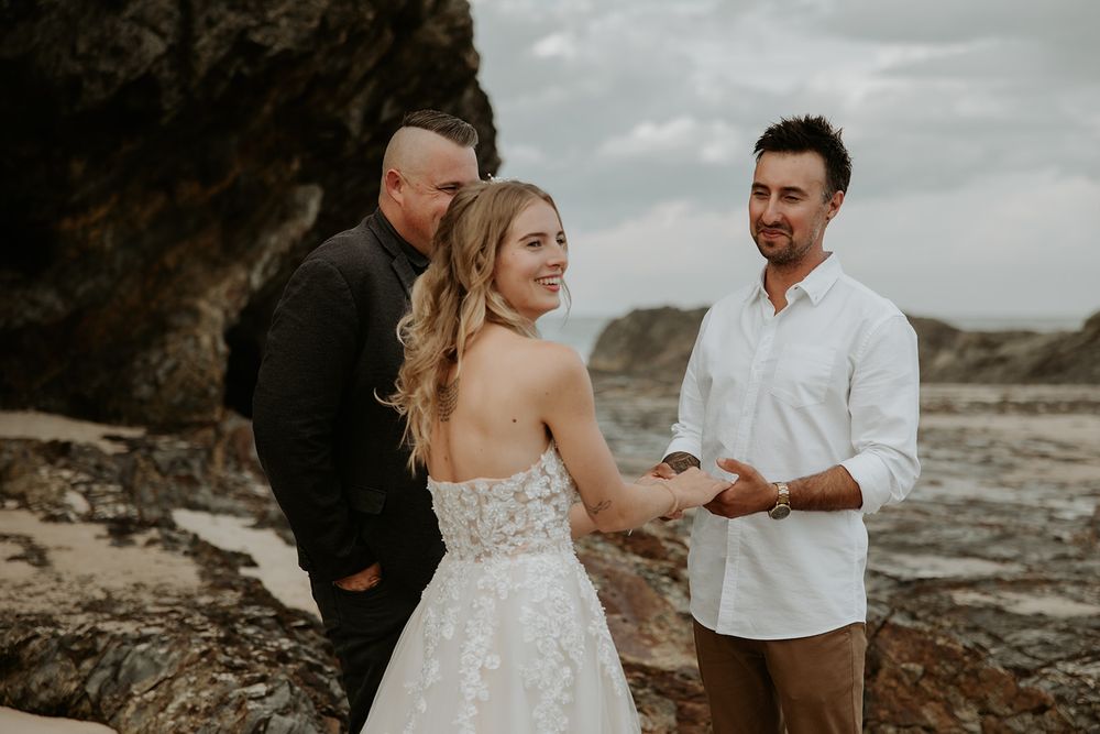 Alana and Nathan holding hands during their Currumbin Rock beach ceremony