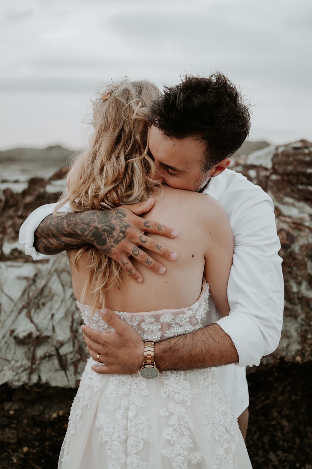 Alana and Nathan embracing beside the rocks at Currumbin Beach