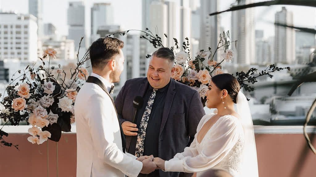 Josh Withers laughing with a couple during their wedding ceremony