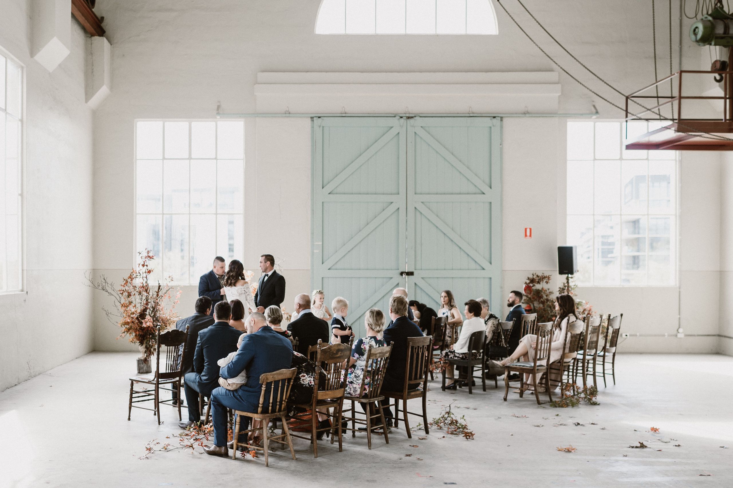 Josh Withers conducting a wedding ceremony in a bright industrial venue in Canberra