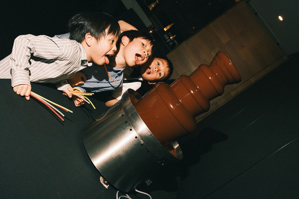 Three young wedding guests pulling playful faces beside Deb and Mickey’s chocolate fountain