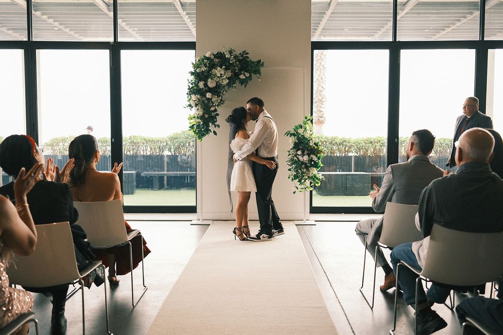 Deb and Mickey kissing at the end of their wedding ceremony while their guests look on