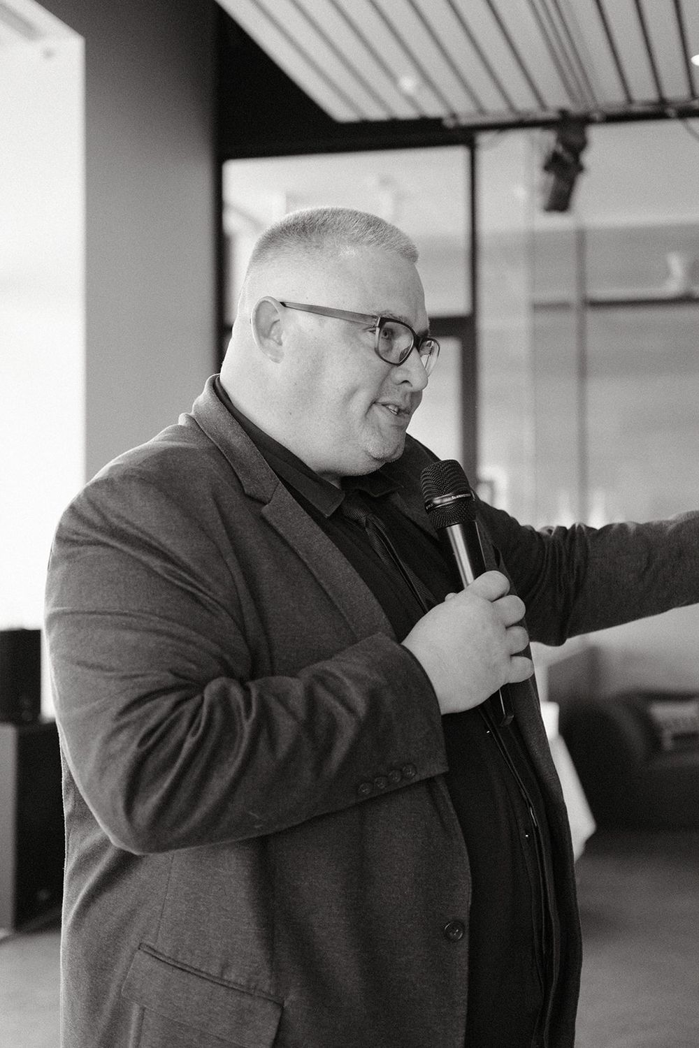 Black and white photograph of Josh Withers speaking into a microphone at Deb and Mickey’s wedding