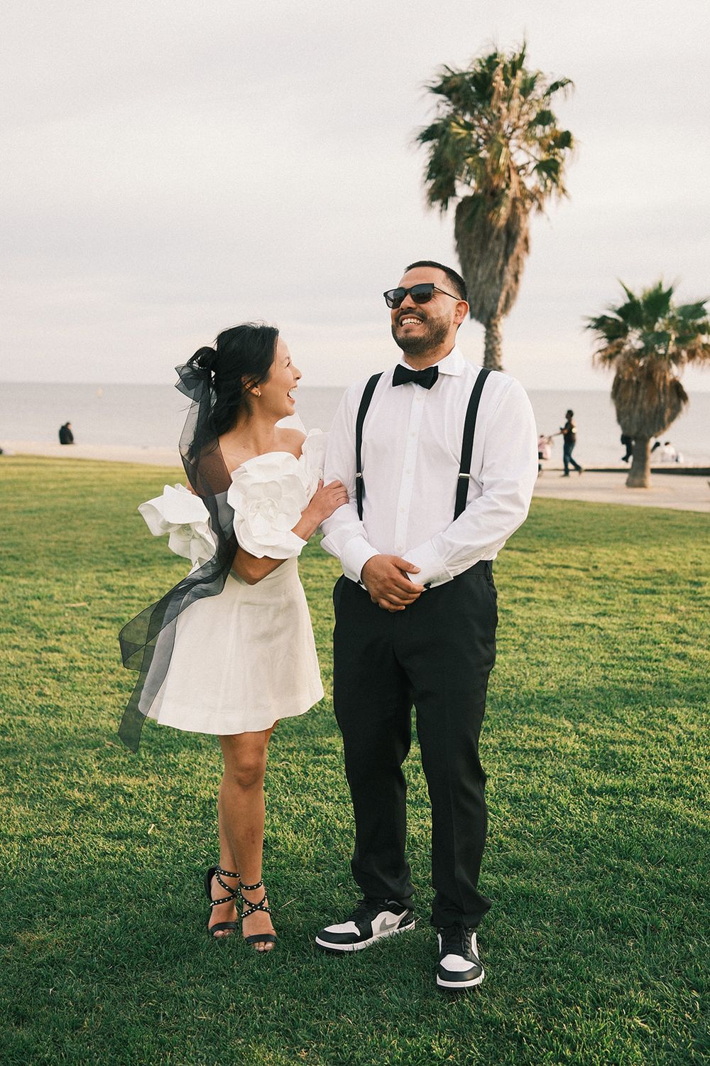 Deb and Mickey holding hands on the grass beneath palm trees