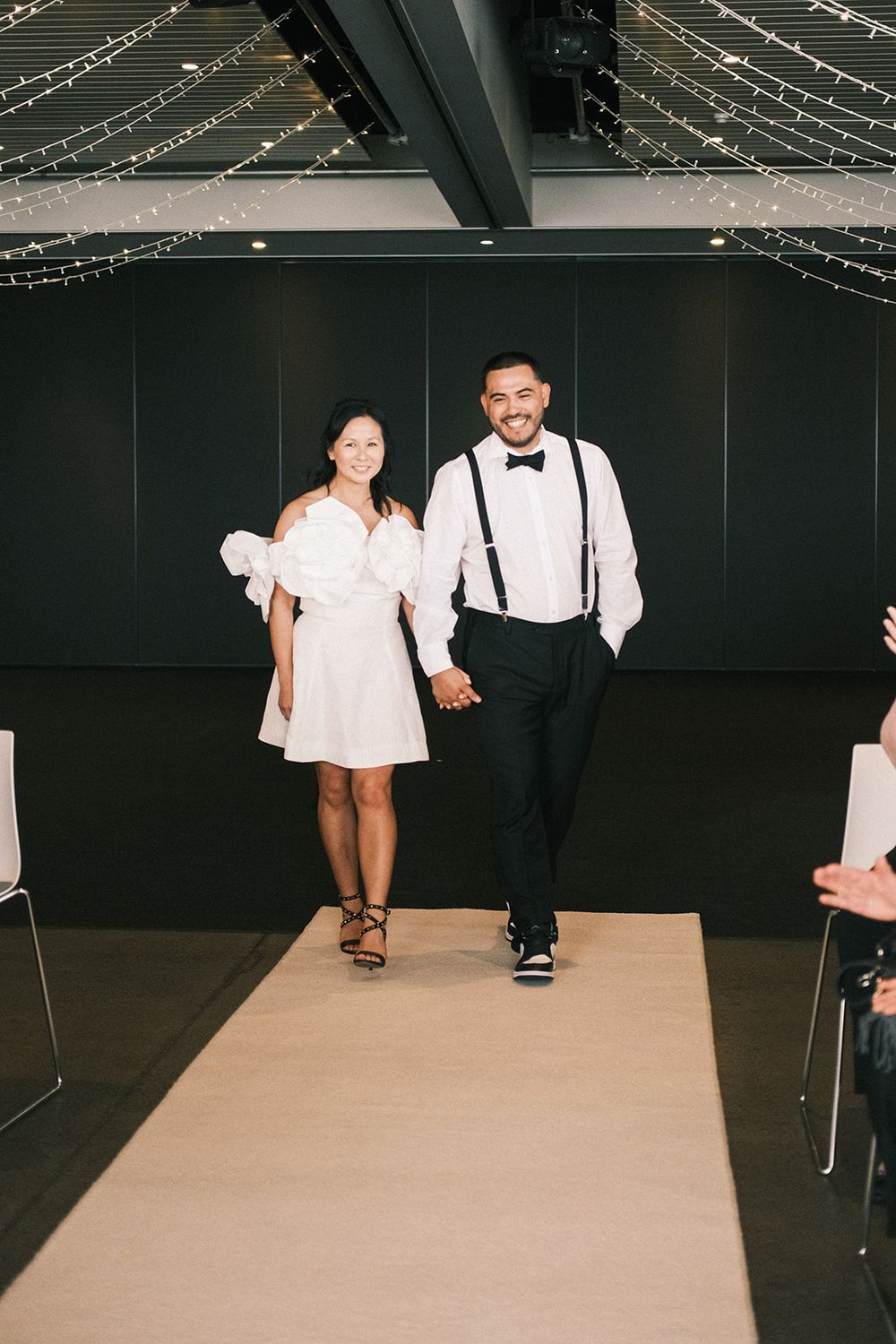 Deb and Mickey smiling and holding hands as they walk into their wedding ceremony together