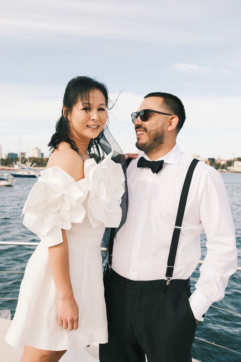 Deb in a short white dress with floral sleeves and Mickey in a bow tie and braces beside the water