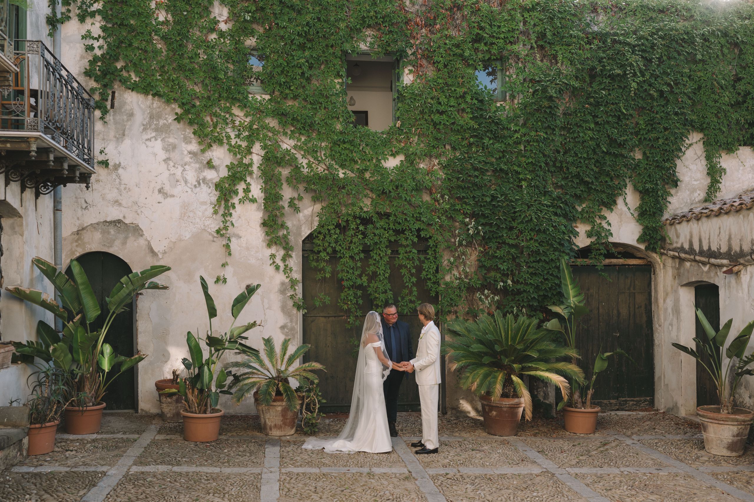 Josh Withers marrying a couple in an ivy-covered courtyard