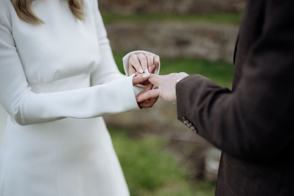 Kaitlyn placing a wedding ring on Russell’s hand during their elopement ceremony