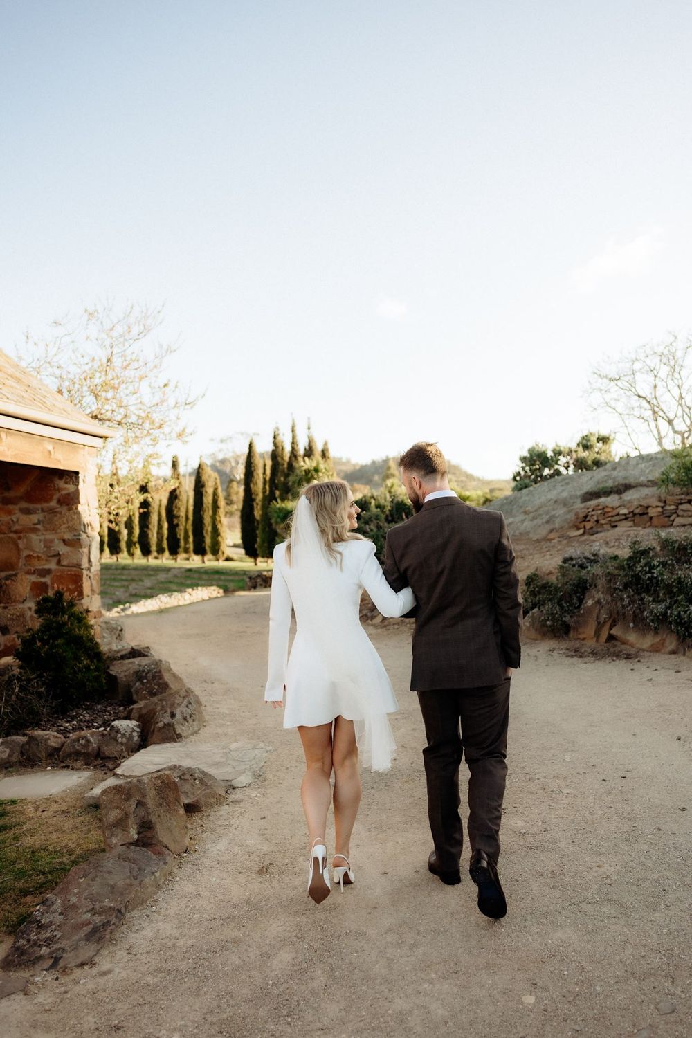 Kaitlyn and Russell walking hand in hand towards the cypress trees at Piermont Retreat