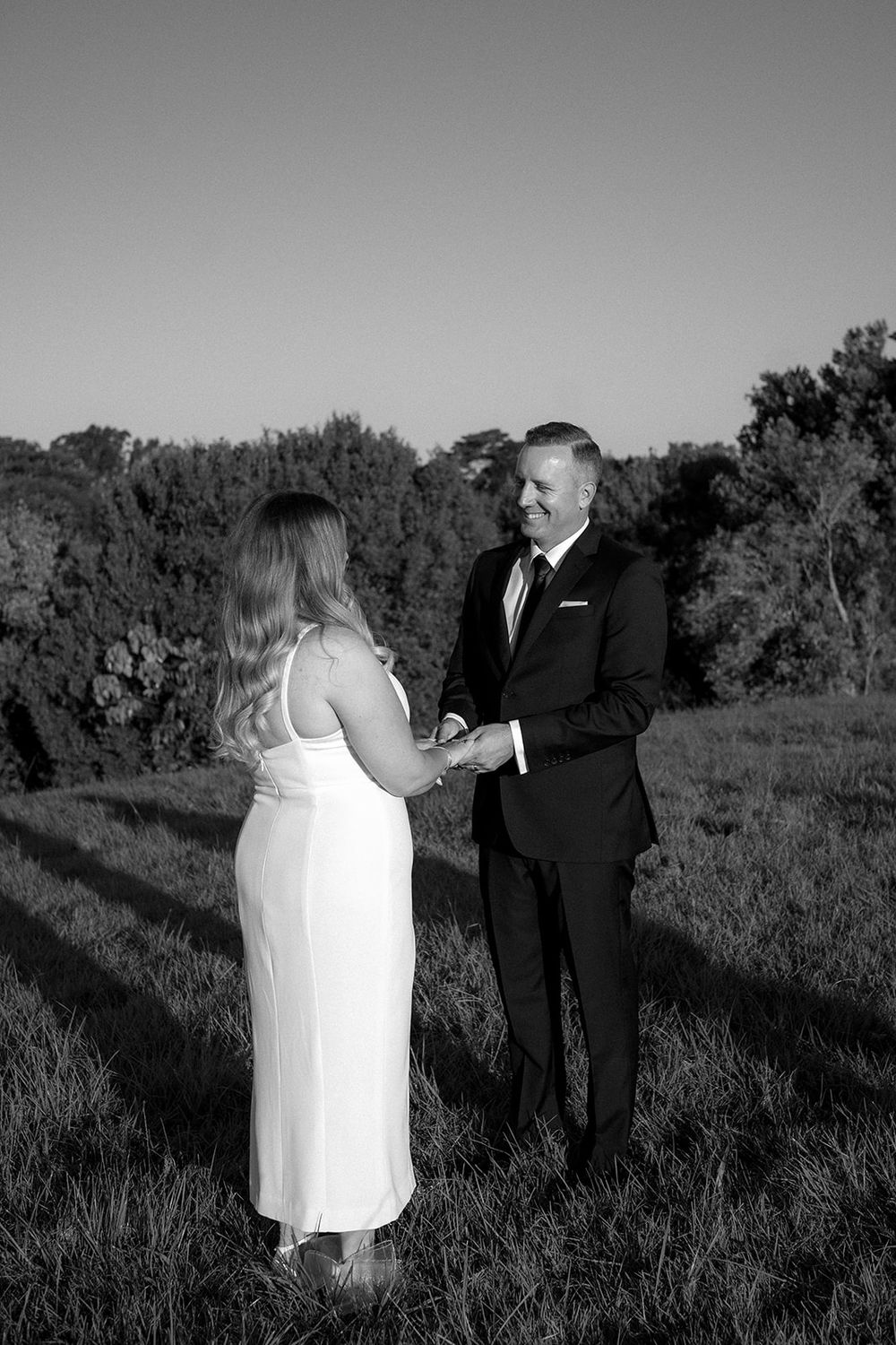 Black and white photograph of Daniel smiling at Libby as they hold hands during their ceremony