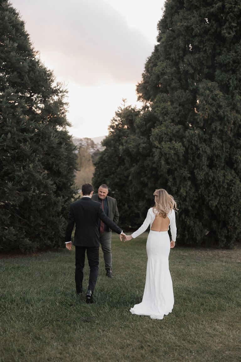 Sarah and Connor holding hands with Josh Withers at their wedding