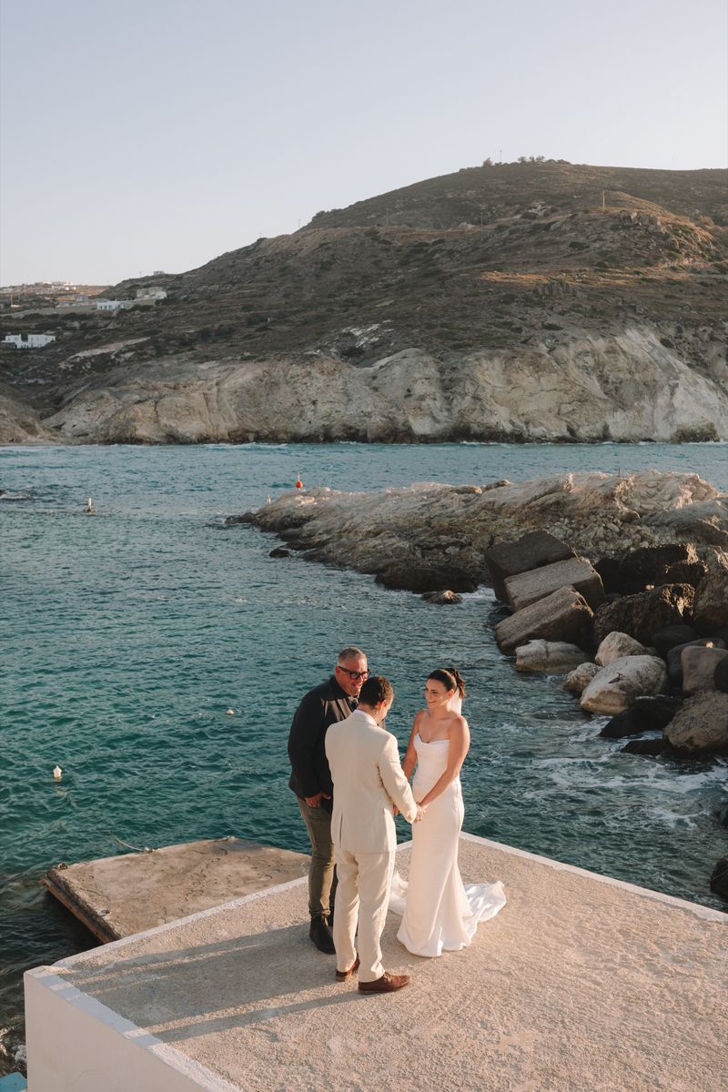 Josh Withers officiating Tiegan and Michael’s waterfront elopement ceremony in Mandrakia, Milos
