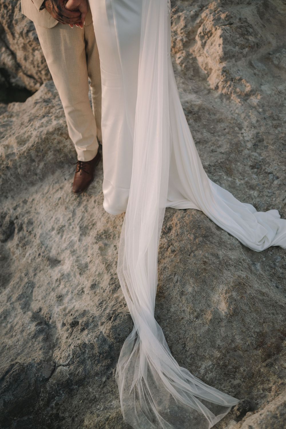 Tiegan and Michael’s wedding clothes and veil draped over volcanic rock at Sarakiniko, Milos